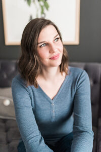 A woman sitting on a couch wearing a blue shirt.