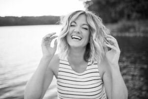 Woman laughing by the river black and white photography.