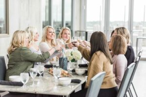 A group of women smiling and raising their glasses in a toast at a table.